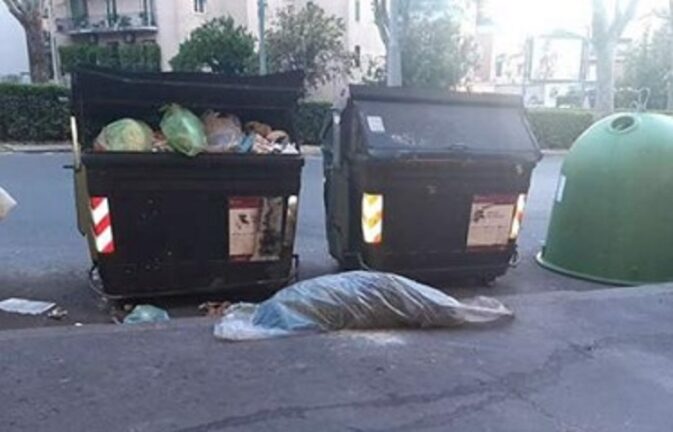 Una donna dorme in sacco di telo, tra i cassonetti come un rifiuto